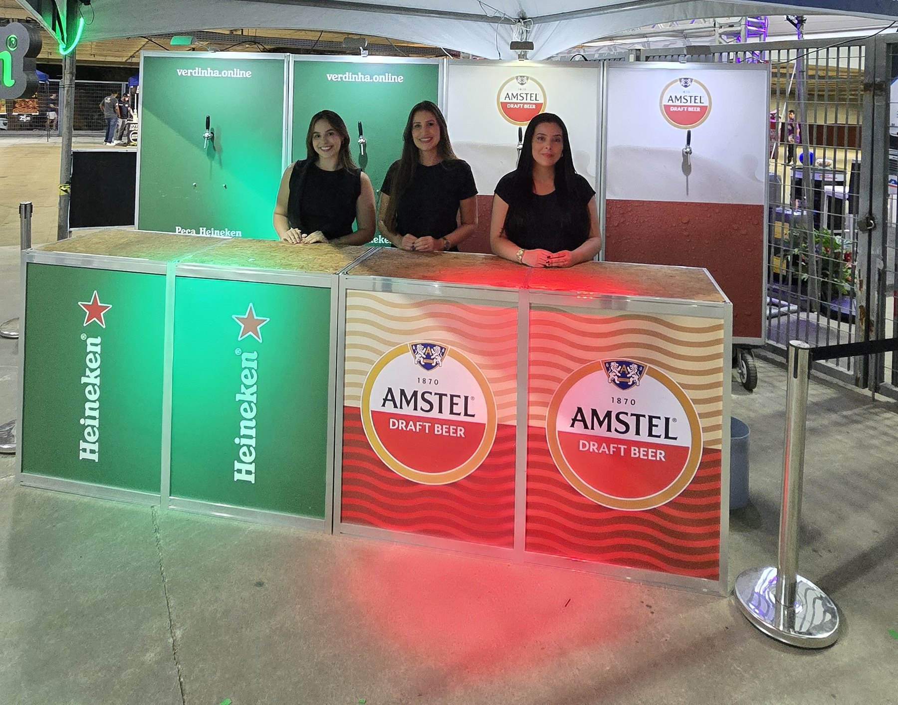 Equipe Verdinha atendendo no balcão de chope com torneiras e comunicação visual Heineken e Amstel