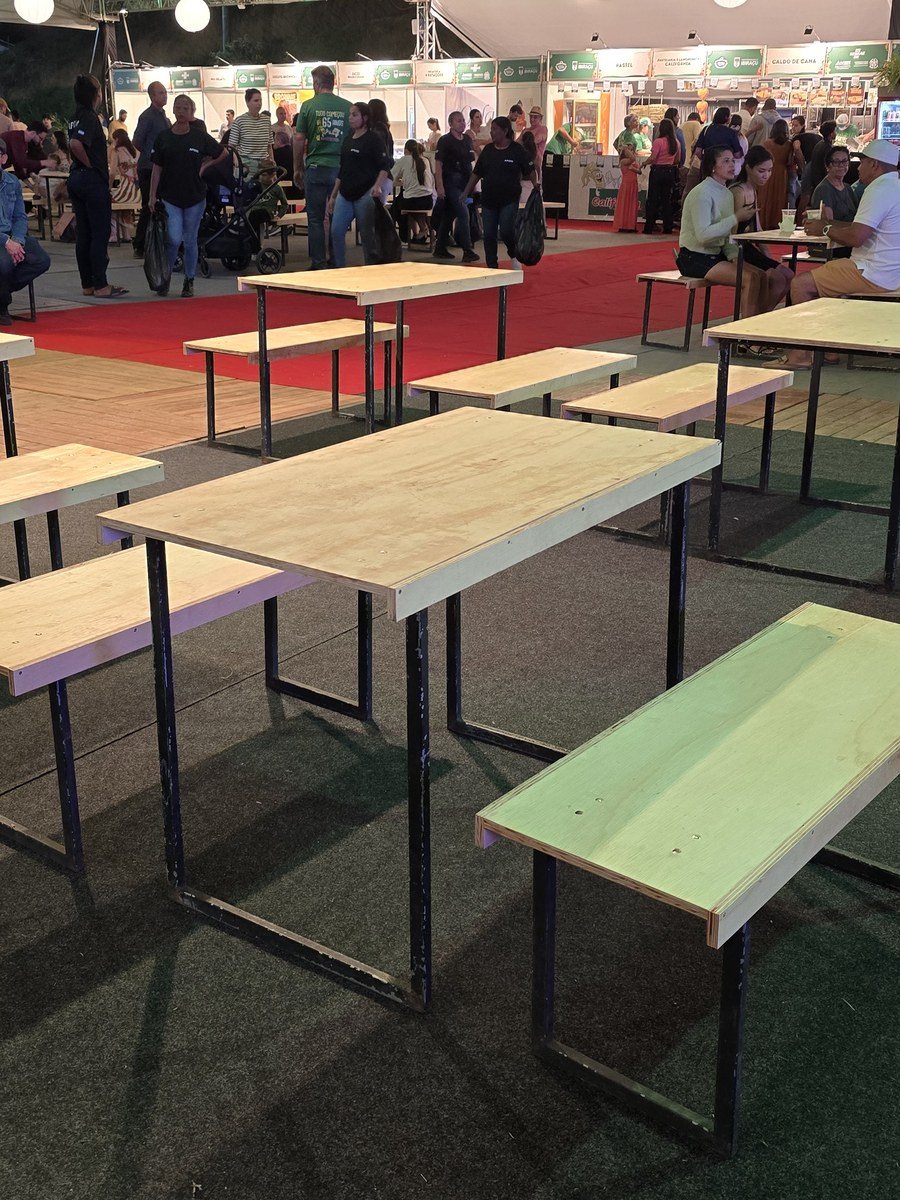 Jogo de mesa de madeira com dois bancos montado em área de evento